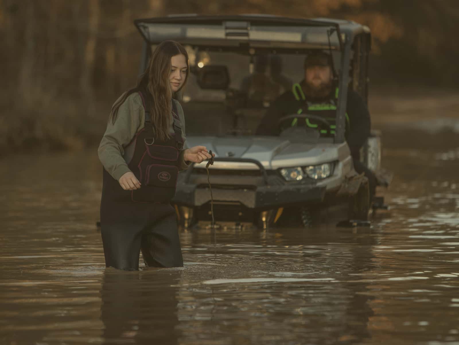 woman in waders in water by ATV